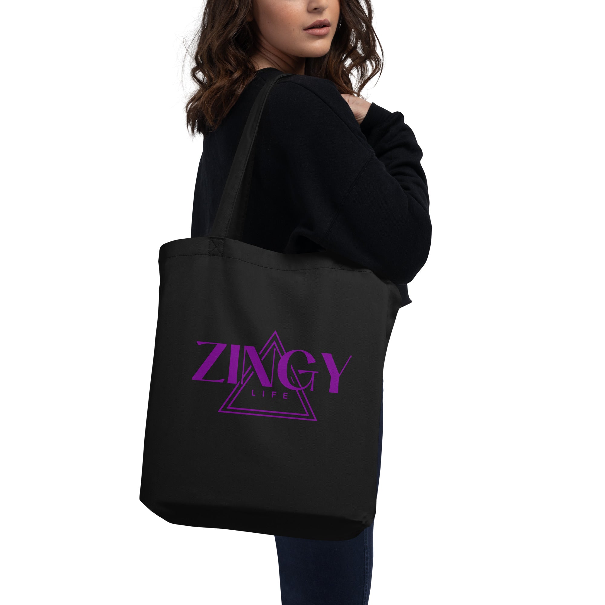 A woman holding a black organic cotton tote bag with the 'ZINGY LIFE' brand logo in purple text on the front.